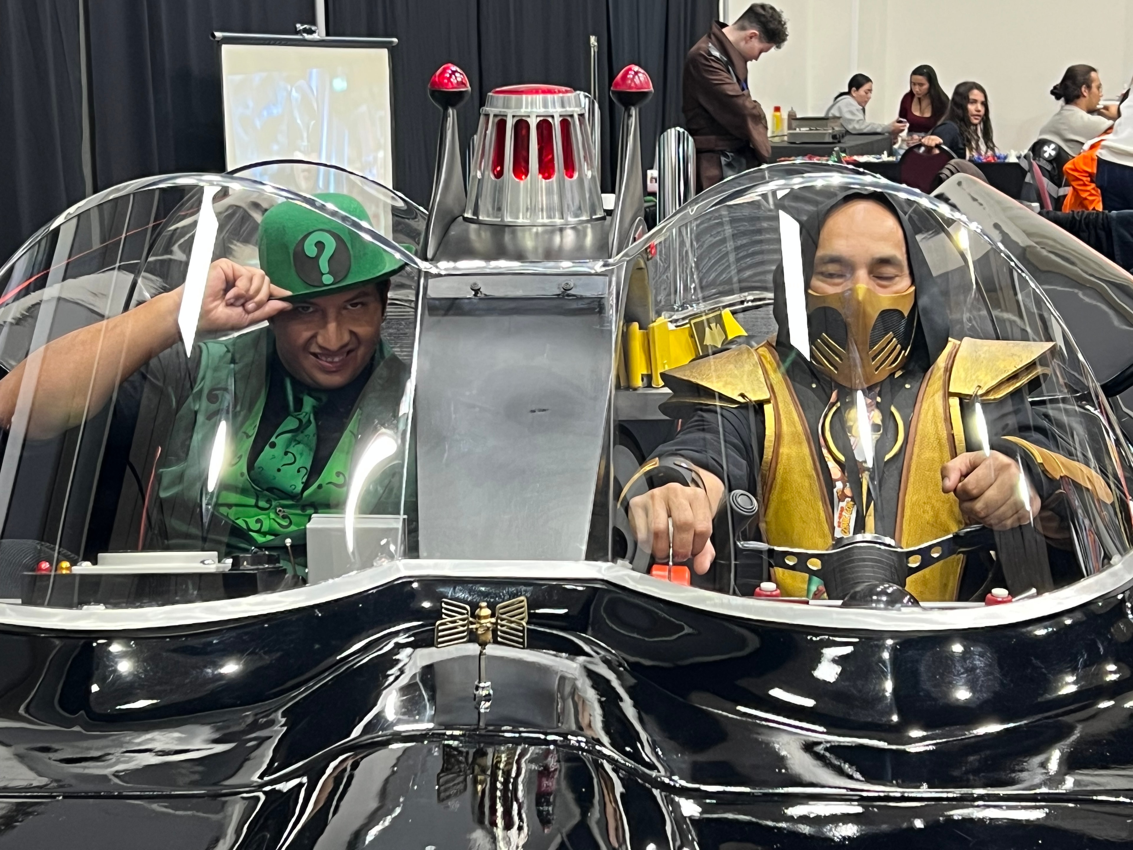 Cosplayers reflected in a convention vehicle display