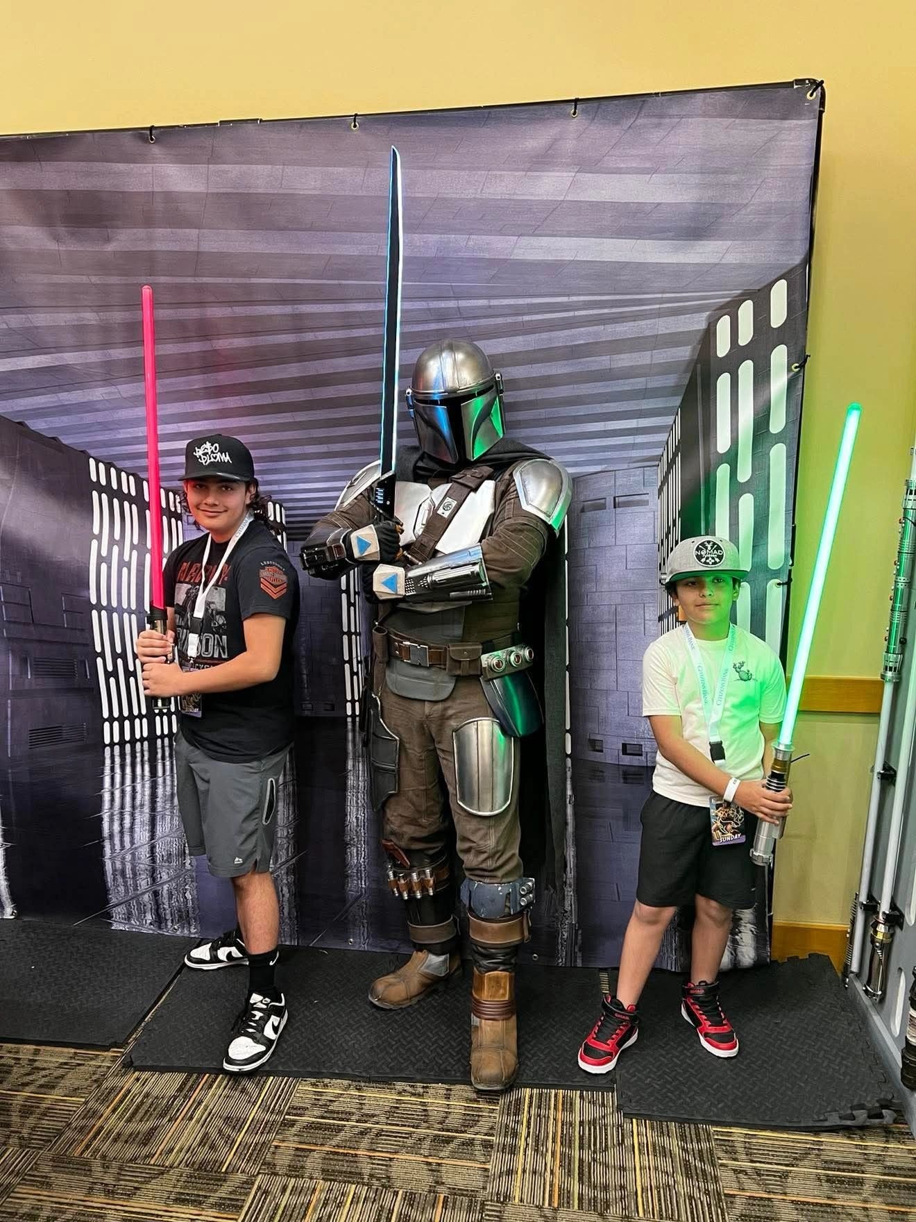 Children posing with the Mandalorian and lightsabers